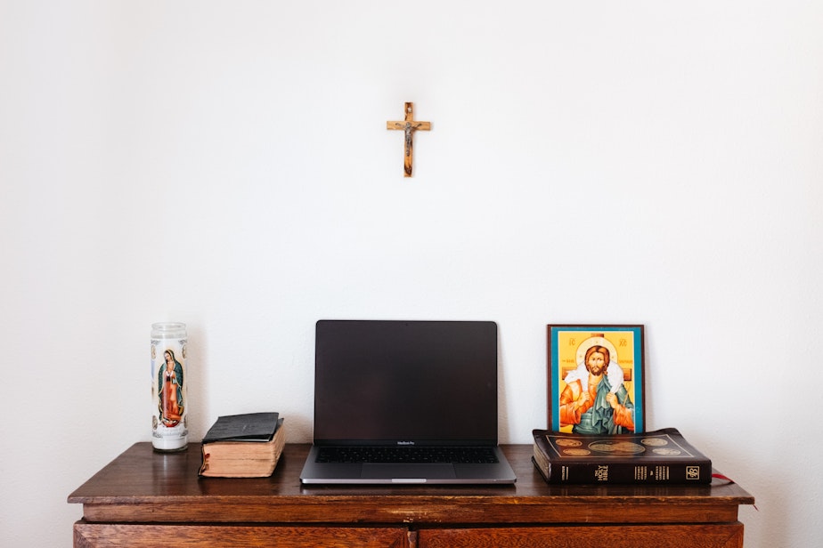 caption: black laptop computer on brown wooden table with various religious materials