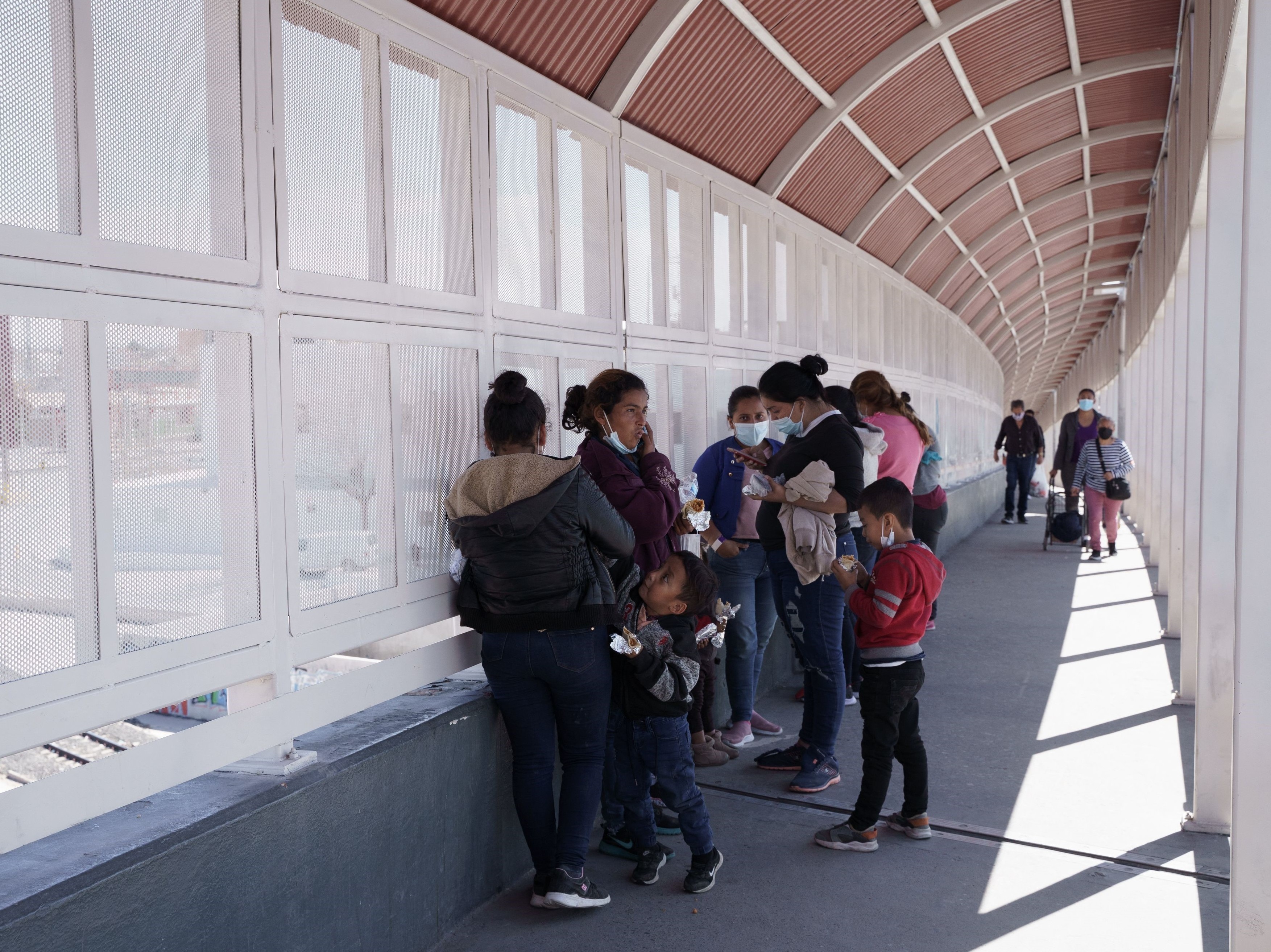 caption: A group of migrants rapidly deported from the U.S. under Title 42 wait on the Mexican side of the Paso del Norte International Bridge, between El Paso, Texas and Ciudad Juarez, Mexico on March 10.