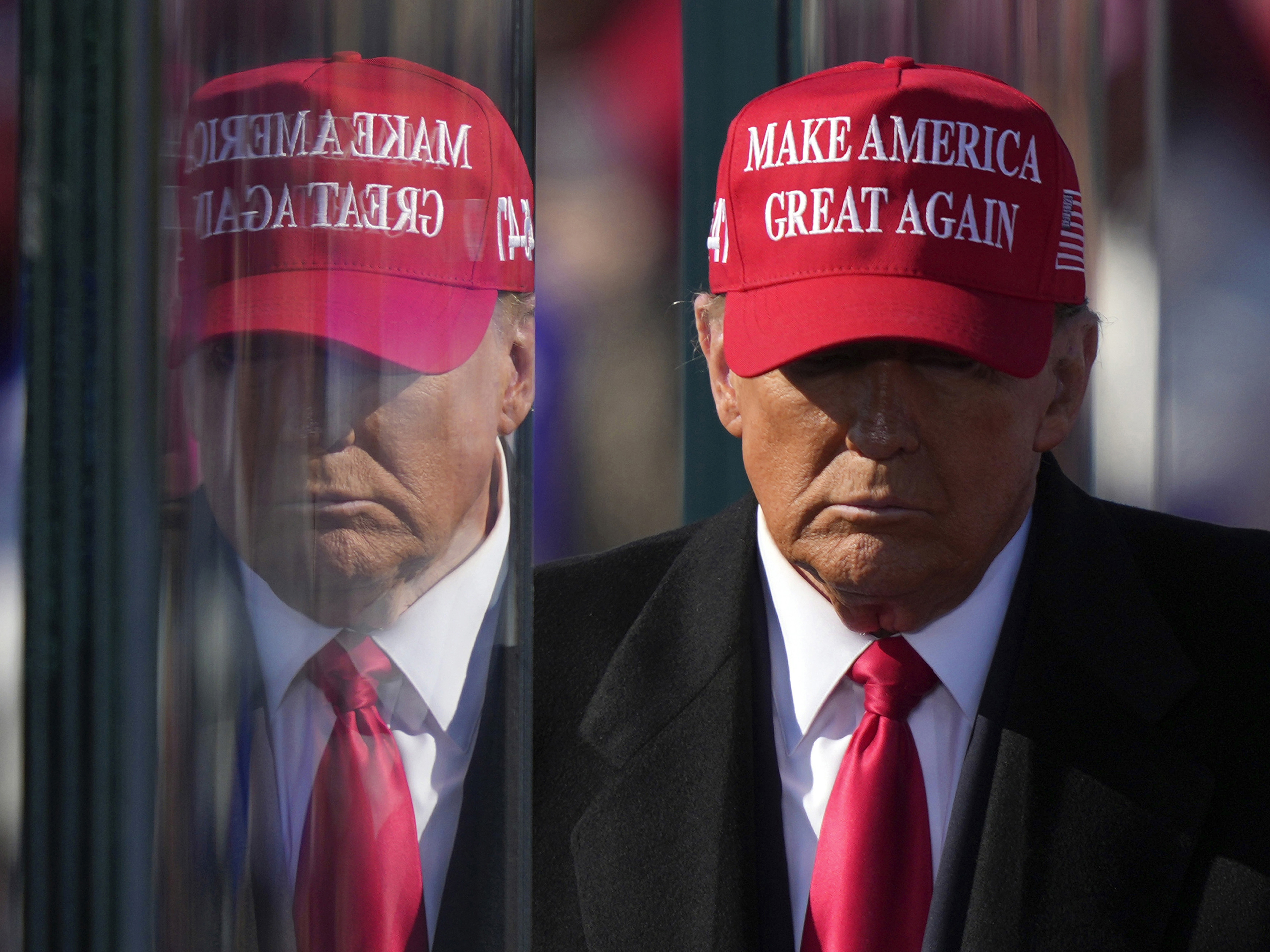 caption: Former President Donald Trump is reflected in the bullet proof glass as he finishes speaking at a campaign rally in Lititz, Pa., on Nov. 3.