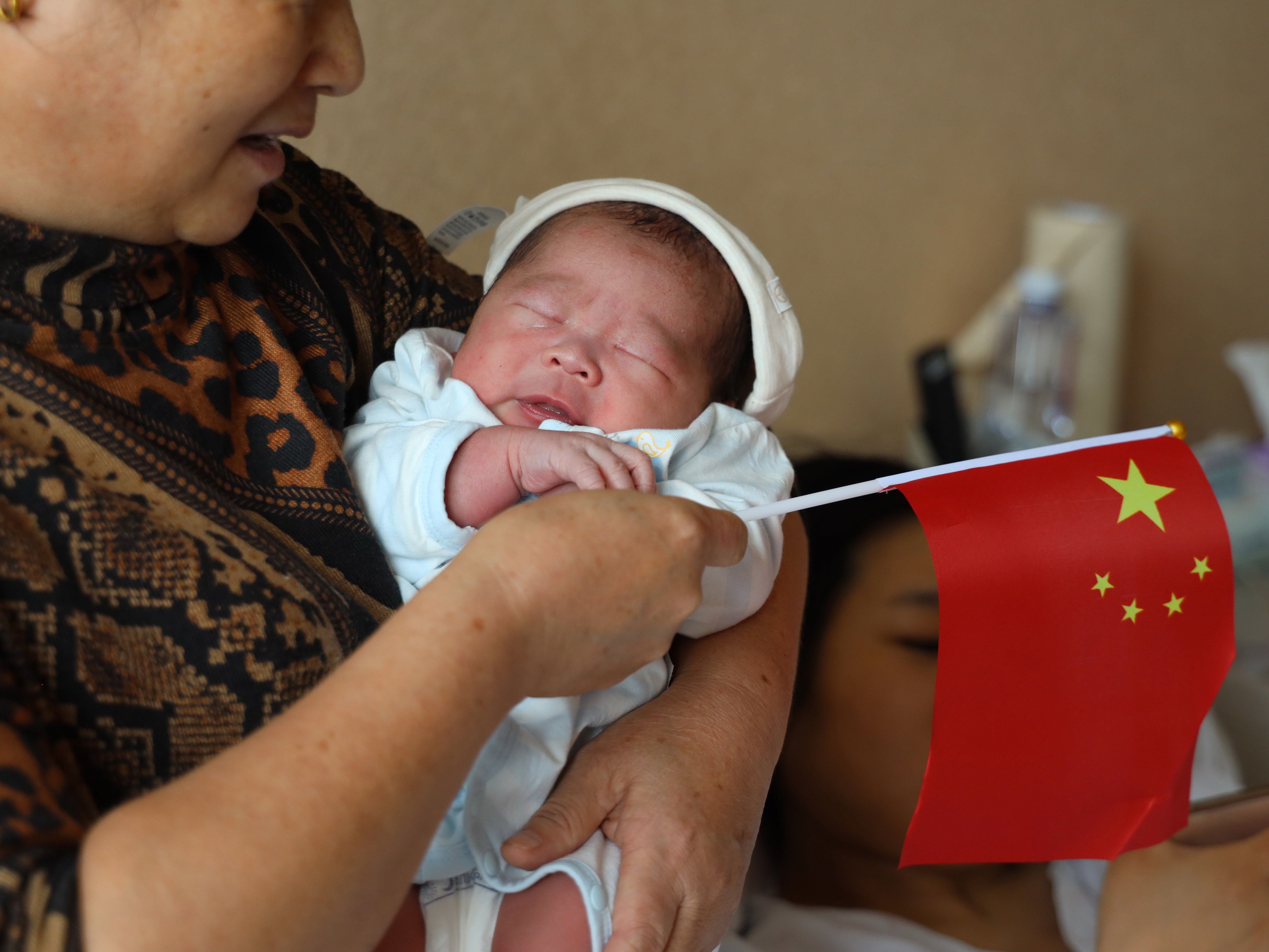 caption: A woman carries a baby born on China's National Day on Oct. 1, 2019, at a hospital in Chengdu, Sichuan Province of China.