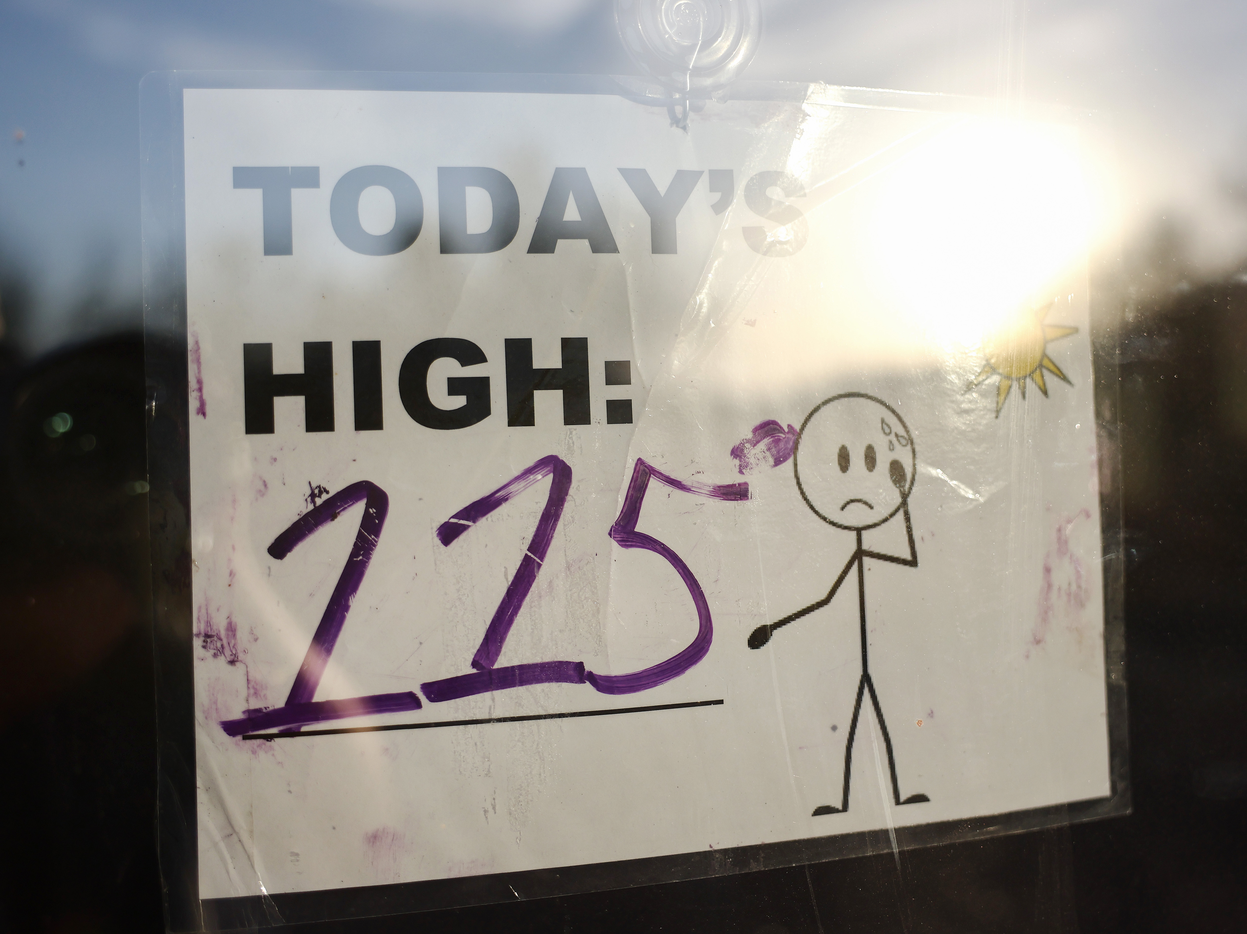 caption: A sign reading "Today's High: 115" is posted in Phoenix, Arizona on July 25.