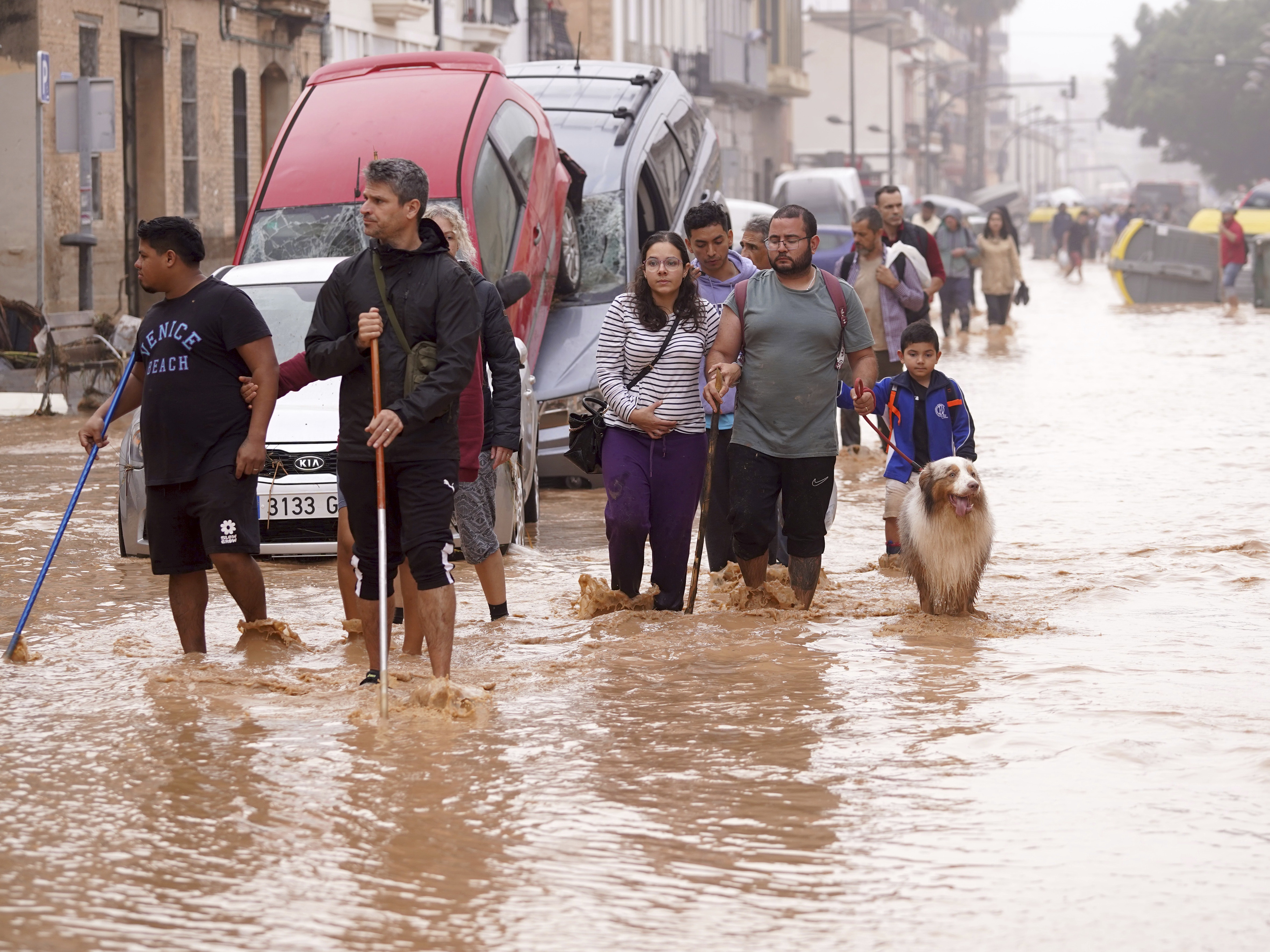 caption: People walk through flooded streets in Valencia, Spain, on Wednesday.