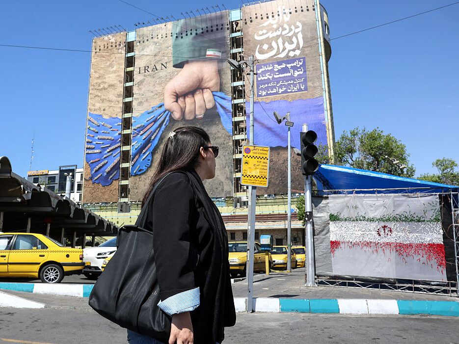 caption: A woman walks past a large billboard referring to the Strait of Hormuz in Vanak Square in Tehran, Iran, on Wednesday.
