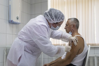 caption: A Moscow health care worker administers a shot of Russia's Sputnik V coronavirus vaccine during clinical trials in September. President Vladimir Putin ordered the nation's health authorities to begin mass vaccinations next week.