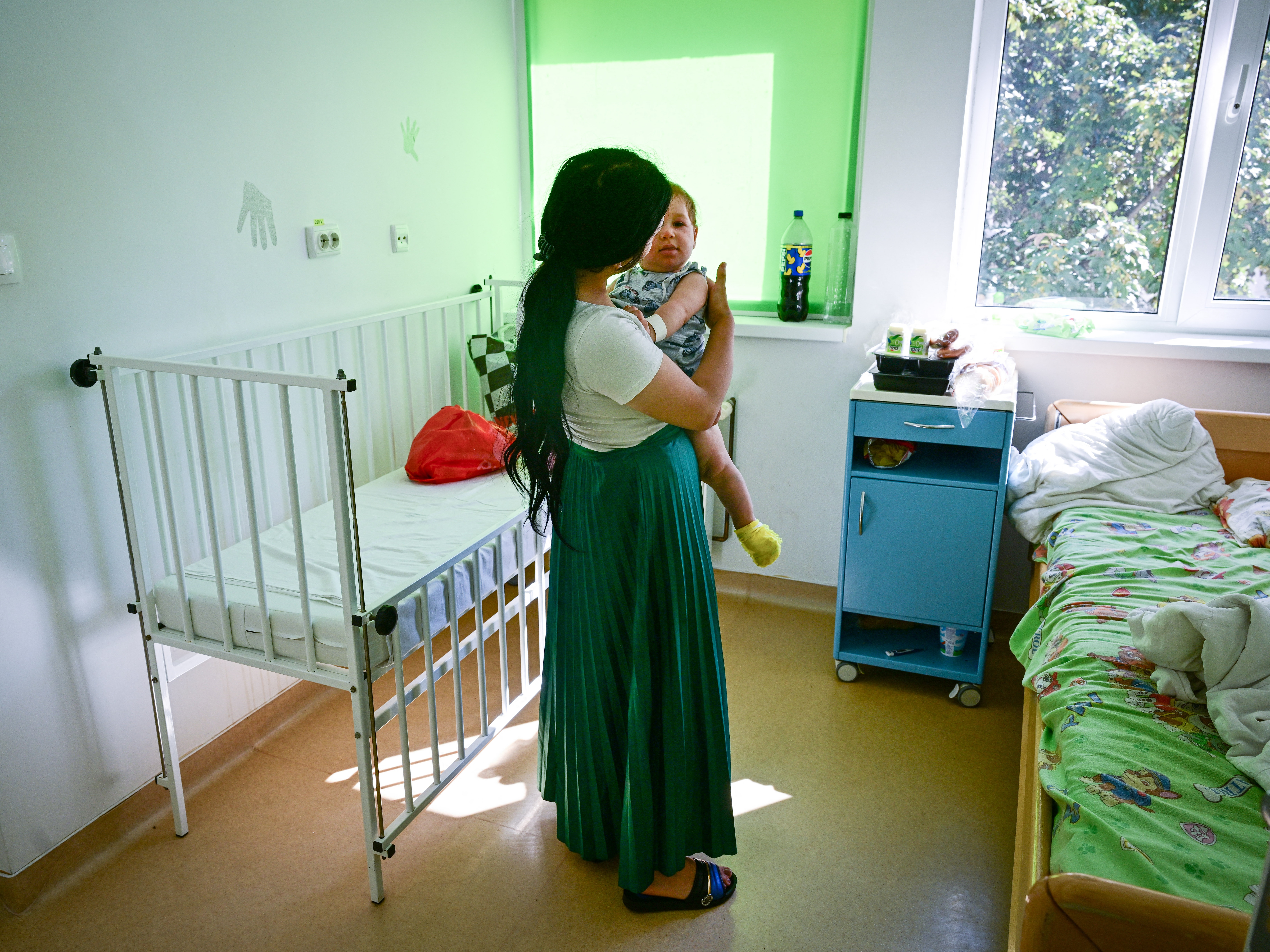 caption: A young mother holds her 10-month-old child, who's suspected of having measles, at a hospital in Piatra Neamt, Romania.