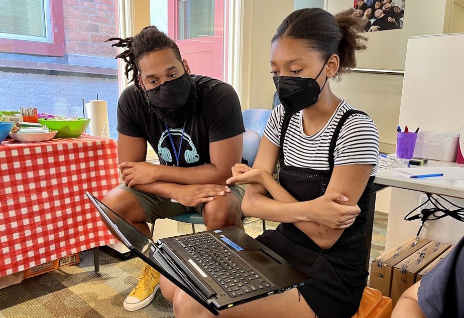 caption: Indigo Mays (right) works on her RadioActive story with support from her mentor Troy Landrum (left) in the RadioActive programming space at KUOW on July 14, 2022. 