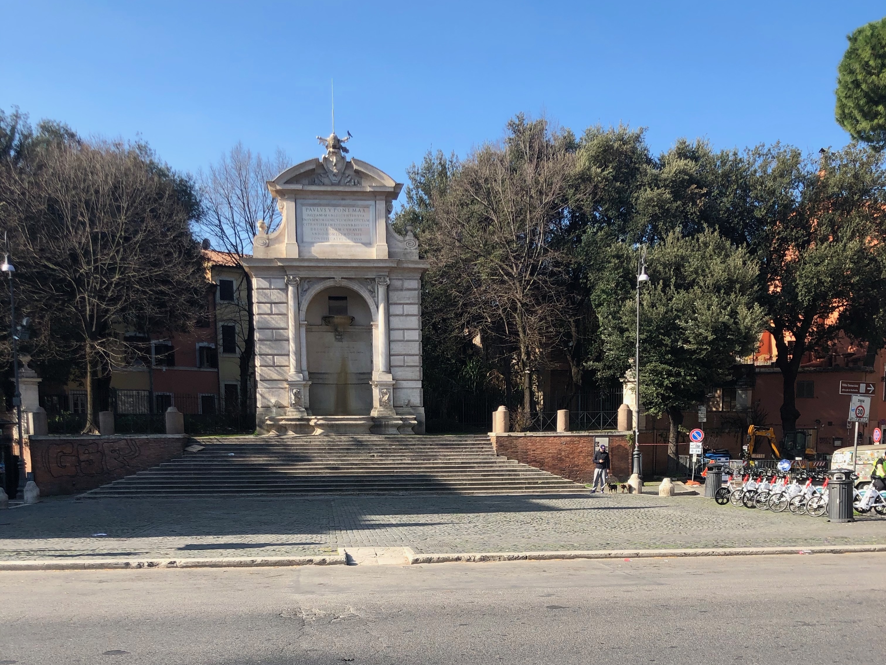 caption: In normal times the pubs and cafes of Piazza Trilussa are the heart of Roman nightlife. Now all is shuttered; the rental bike stand is full and the only sound is the waterfall in the fountain.