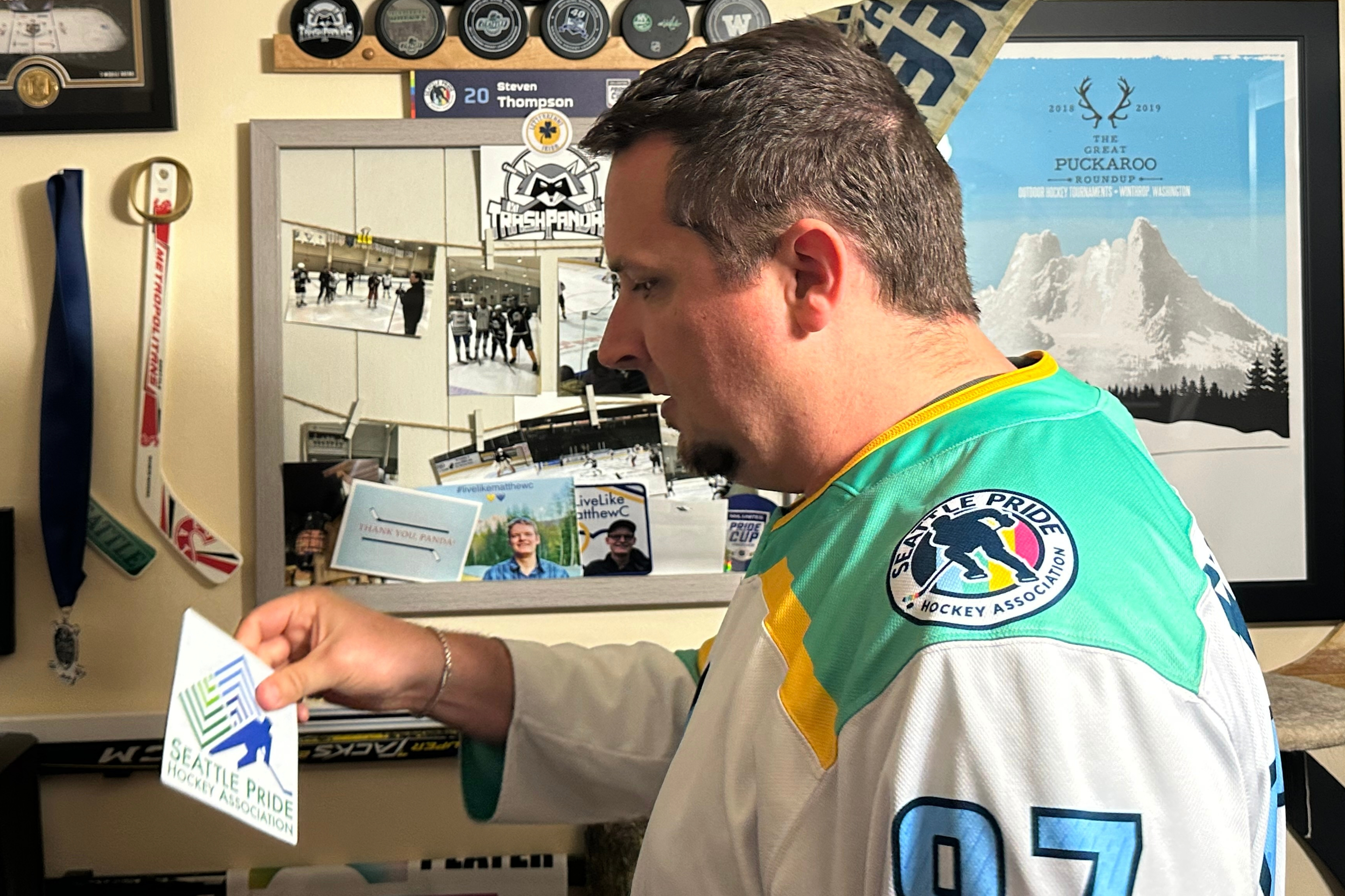 caption: Steven Thompson, co-founder of the Seattle Pride Hockey Association (SPHA), sifts through some of his hockey memorabilia at his home in Des Moines, Wash., Monday, April 27, 2026. 