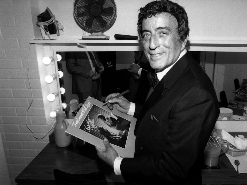 caption: Tony Bennett poses while signing an autograph in 1988.