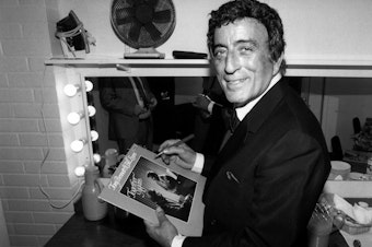 caption: Tony Bennett poses while signing an autograph in 1988.