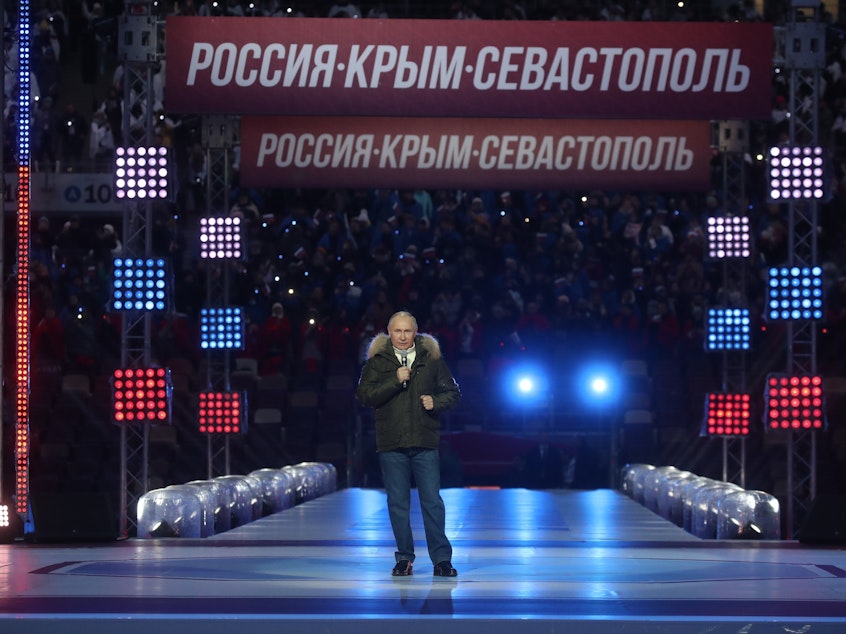 caption: Russian President Vladimir Putin speaks Thursday prior to a concert marking the seventh anniversary of the annexation of Crimea from Ukraine. The banner behind him reads: RUSSIA-CRIMEA-SEVASTOPOL."