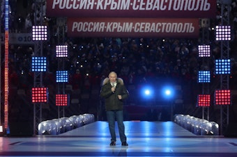 caption: Russian President Vladimir Putin speaks Thursday prior to a concert marking the seventh anniversary of the annexation of Crimea from Ukraine. The banner behind him reads: RUSSIA-CRIMEA-SEVASTOPOL."