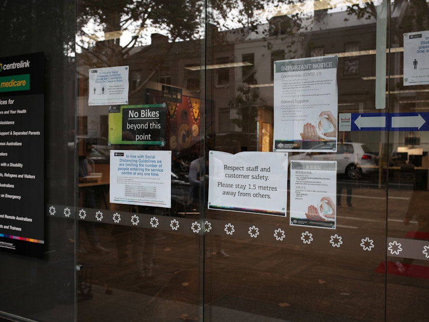 caption: In Sydney earlier this week, signs urge social distancing and emphasize hand-washing to stave off COVID-19.