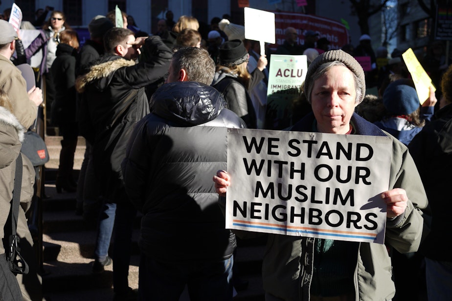 caption: FILE: Therese Macisaac of Seattle joins a protest against the travel ban outside the U.S. District Court of Appeals in Seattle in 2017.