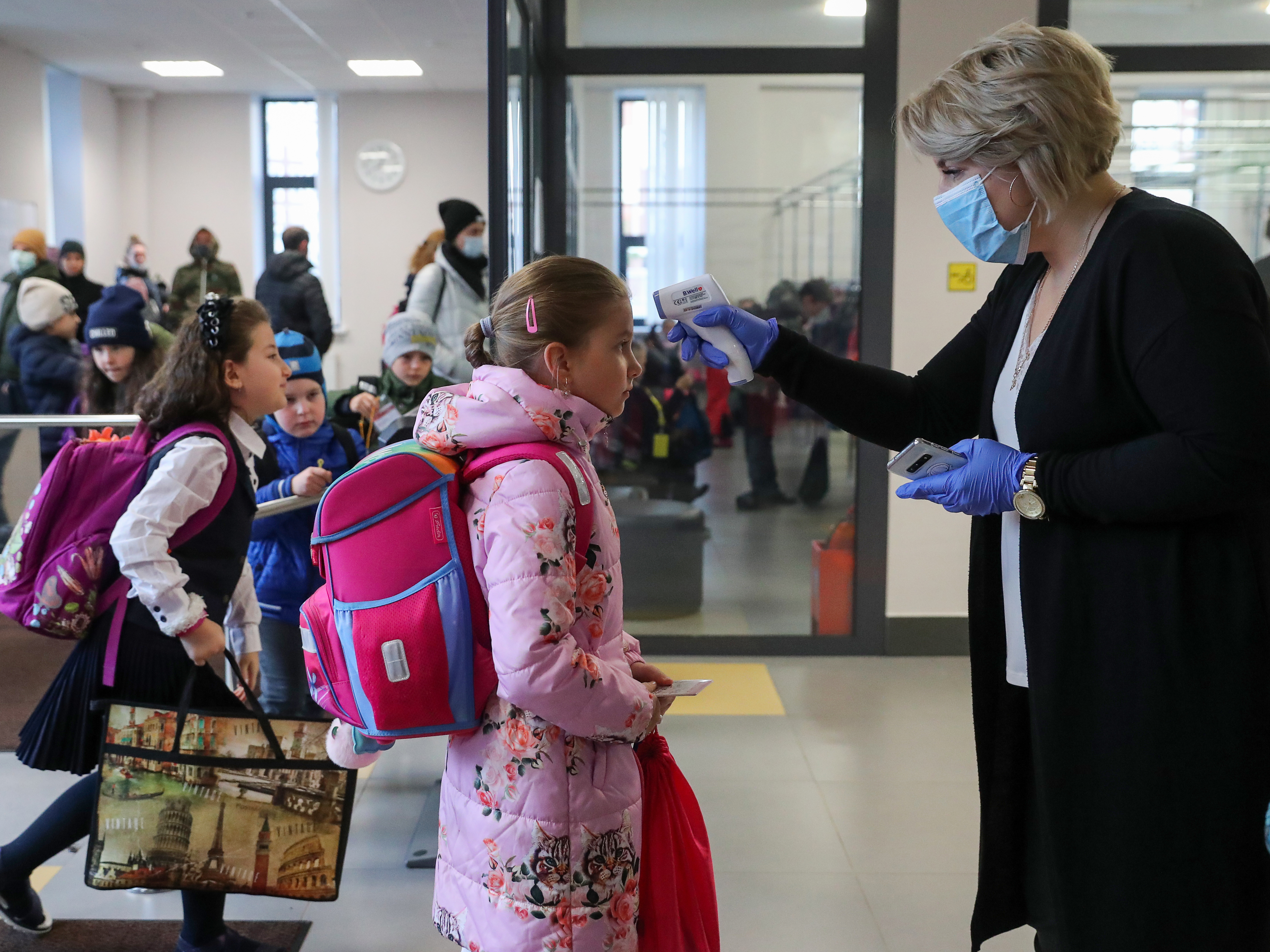 caption: More than 40 million coronavirus infections have now been reported worldwide. Here, a staff member at a school in Moscow uses an infrared thermometer on Monday to screen students. Moscow schools reopened after a two-week fall holiday, but a rise in cases means only primary school pupils will be in classrooms.