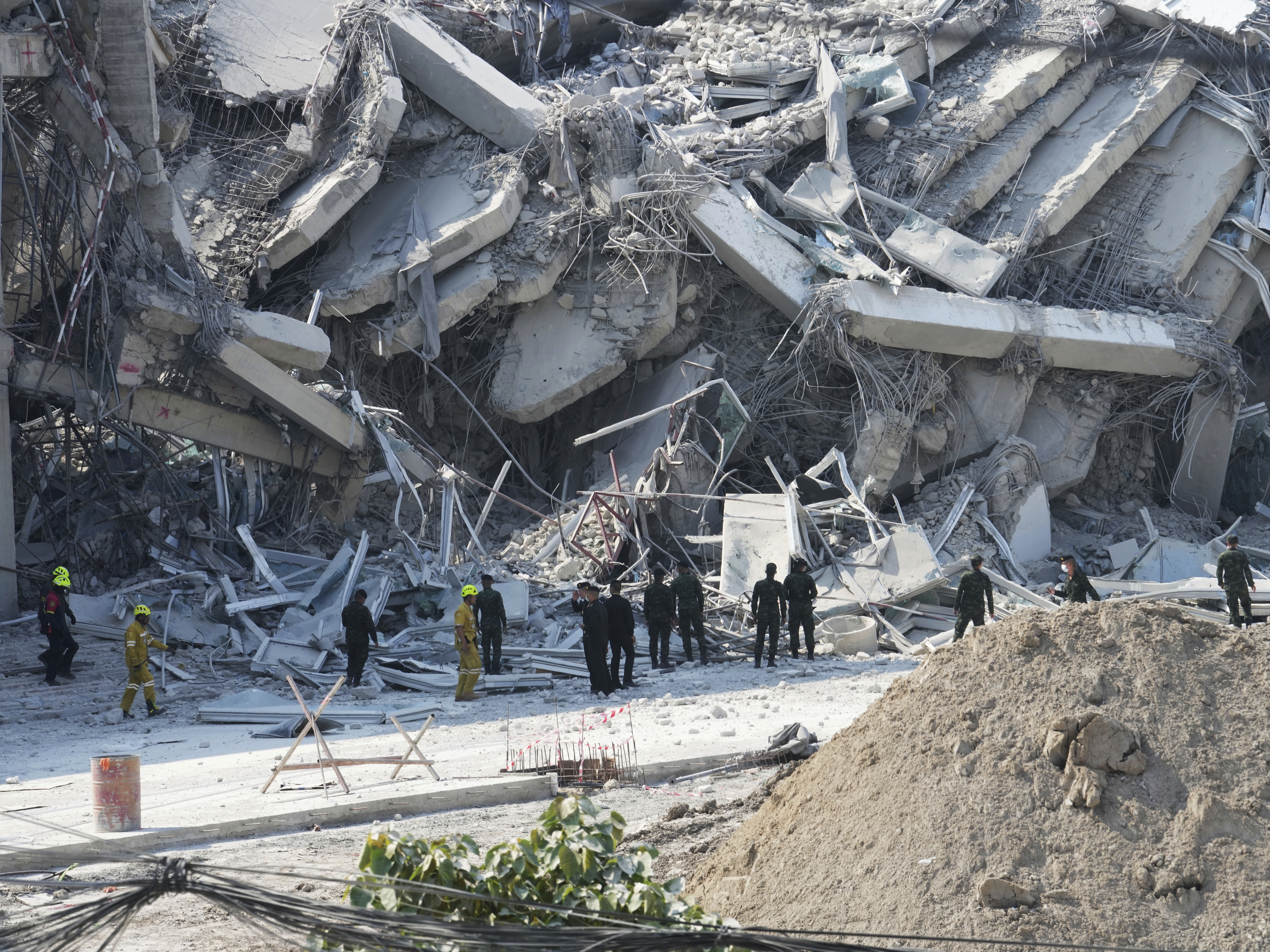 caption: Rescuers work at the site of a high-rise building under construction that collapsed after a 7.7 magnitude earthquake in Bangkok on Friday.