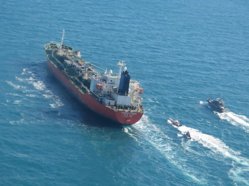 caption: A seized South Korean-flagged tanker is escorted by Iranian Revolutionary Guard boats in the Persian Gulf. This comes as Tehran is enriching nuclear fuel to 20% purity.