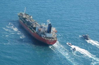 caption: A seized South Korean-flagged tanker is escorted by Iranian Revolutionary Guard boats in the Persian Gulf. This comes as Tehran is enriching nuclear fuel to 20% purity.