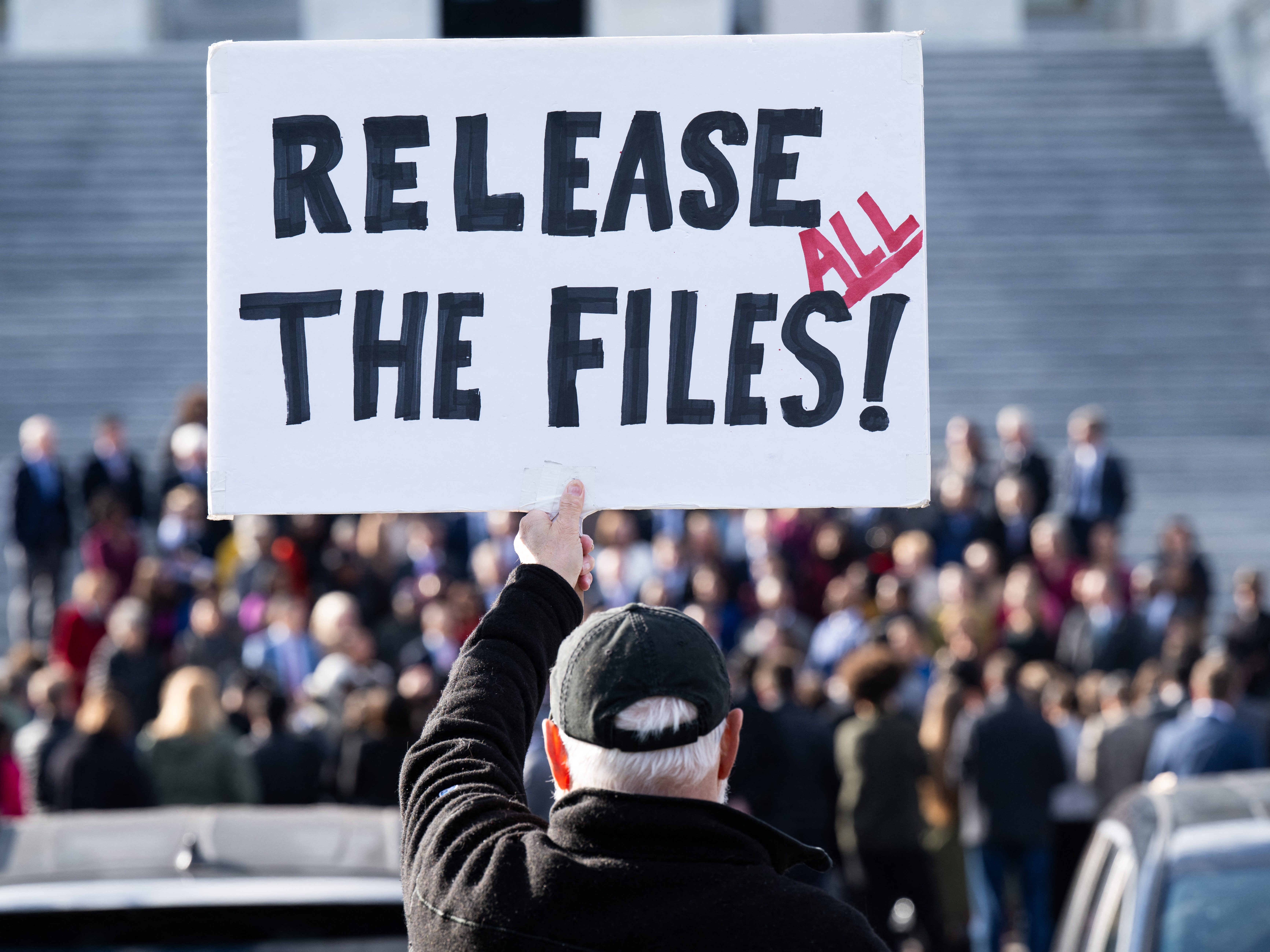 caption: A protester holds a sign related to the release of the Jeffrey Epstein case files outside the U.S. Capitol in Washington, DC, on November 12, 2025.
