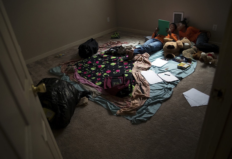 caption: Matthew and Mariah Hicks read together in the new bedroom that they share on Saturday, September 16, 2017, in Auburn.