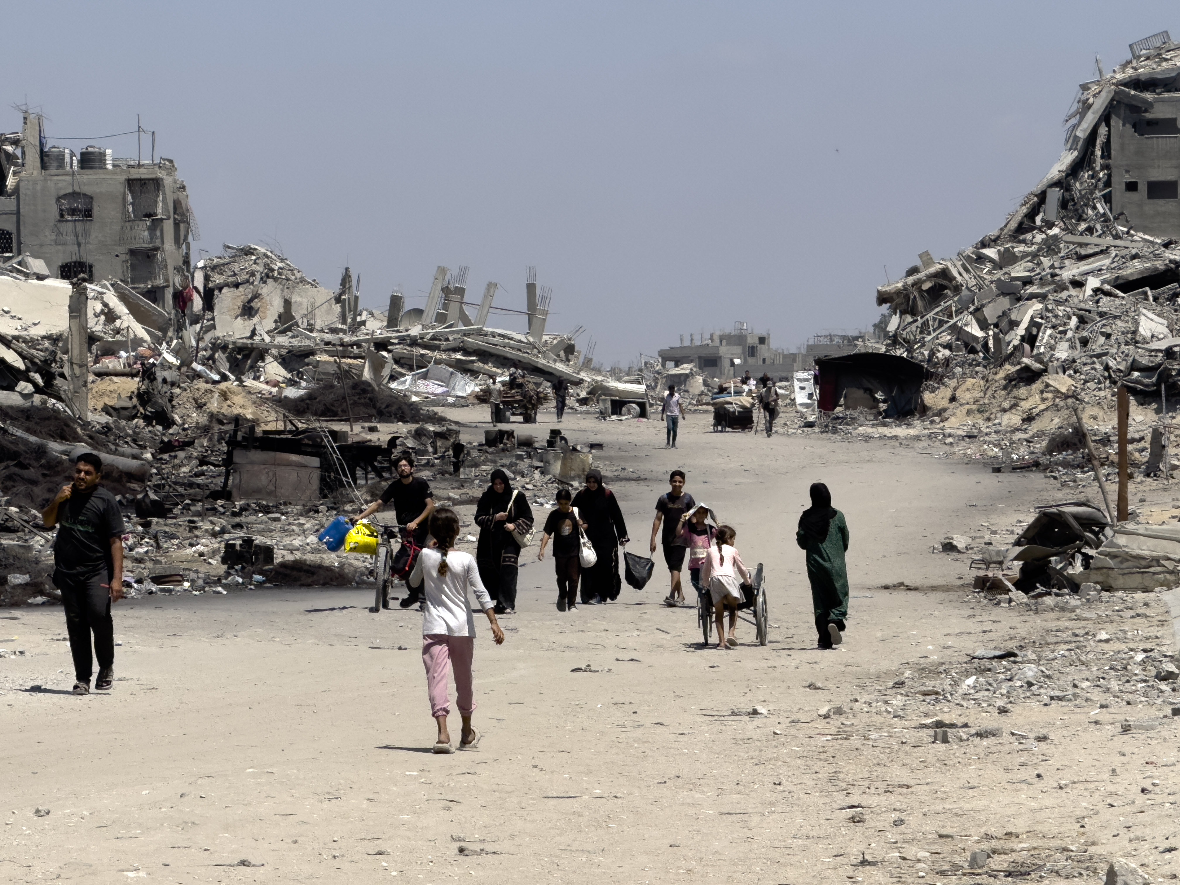 caption: Families leave northern neighborhoods of Gaza City with the few items they can carry on Aug. 26, after Israeli tanks and airstrikes force them out.
