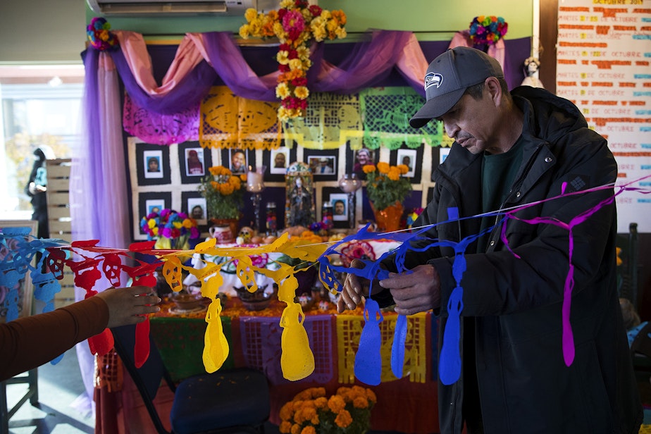caption: Benito Ayala untangles a portion of the Day of the Dead altar on Tuesday, October 29, 2019, at Casa Latina in Seattle.