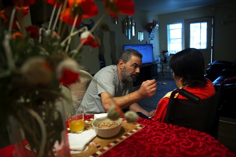caption: Omar, left, feeds his wife Marta, right, at their apartment on Tuesday, September 26, 2023, in Everett. 
