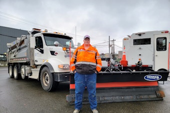 caption: Peter Siegl stands next to his Peterbilt dump truck on Tuesday, Nov. 7, 2023.
