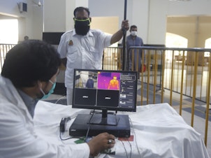 caption: Railway staff in Pakistan use a thermal scanner to check visitors for coronavirus symptoms. Pakistan was one of the nine countries added to the U.N.'s new aid plan.