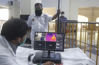 caption: Railway staff in Pakistan use a thermal scanner to check visitors for coronavirus symptoms. Pakistan was one of the nine countries added to the U.N.'s new aid plan.
