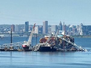 caption: Salvage crews in Baltimore continue to remove wreckage from the Dali on April 26, one month after the cargo ship smashed into the Francis Scott Key Bridge and caused it to collapse.