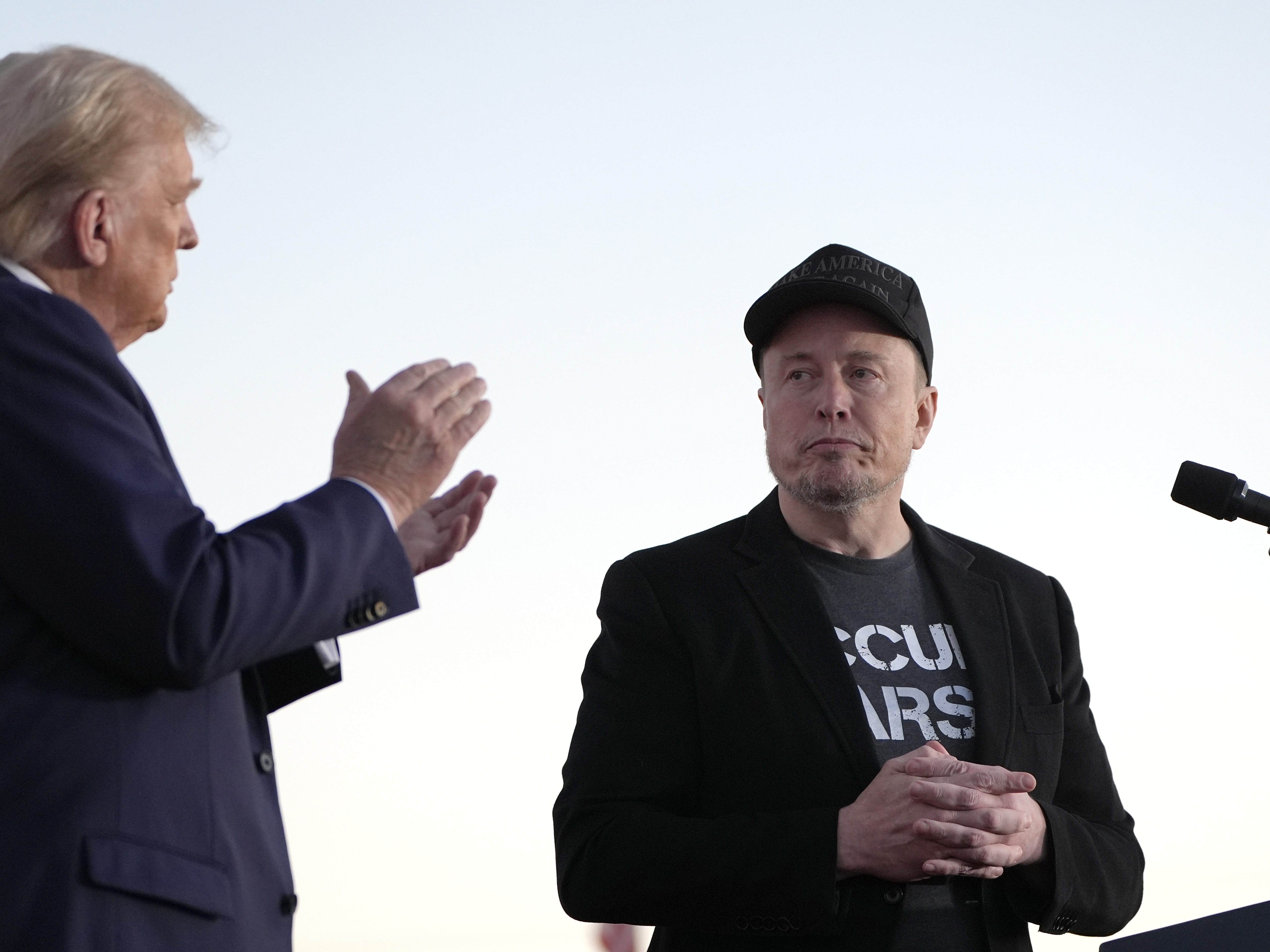 caption: Republican presidential nominee former President Donald Trump, left, claps as Tesla and SpaceX CEO Elon Musk prepares to depart after speaking at a campaign event at the Butler Farm Show, on Oct. 5, 2024, in Butler, Pa.