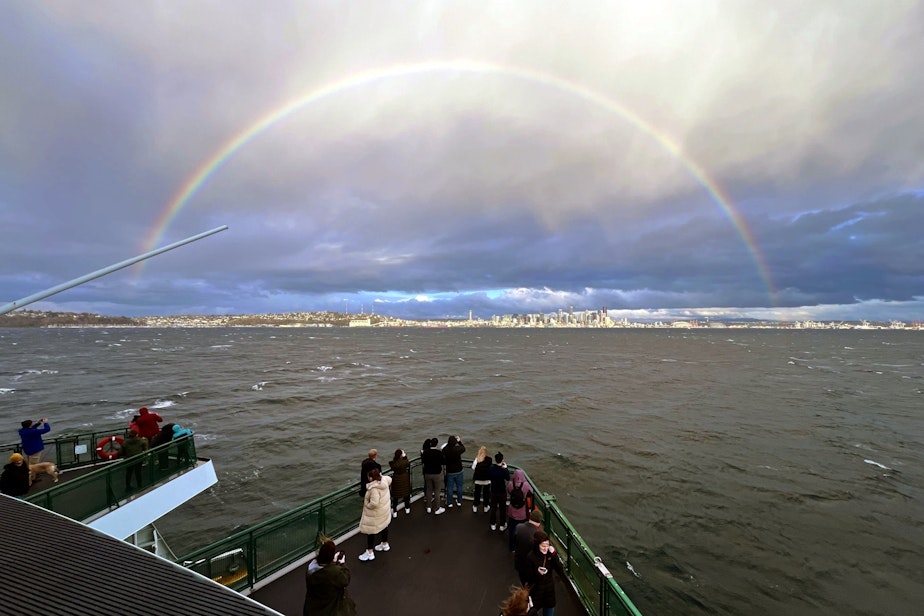 caption: A rainbow over Seattle captures the attention of ferry riders from Bainbridge Island on March 9, 2024.