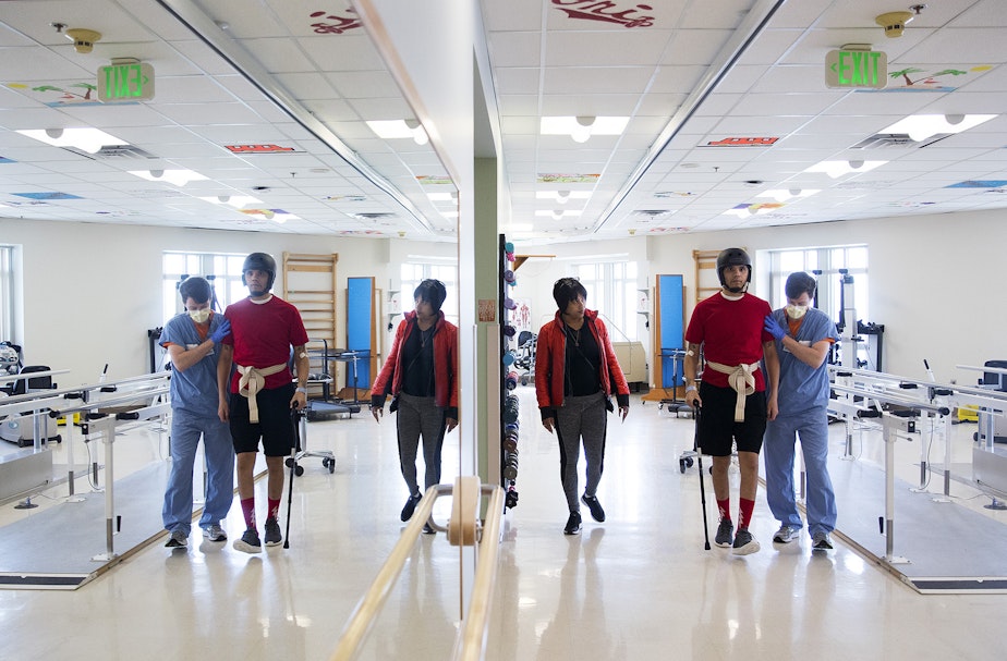 caption: DaShawn Horne learns how to walk again as his physical therapist Trevor Bouten holds him up, as his mother LaDonna Horne watches on Thursday, April 26, 2018, at Harborview Medical Center in Seattle.
