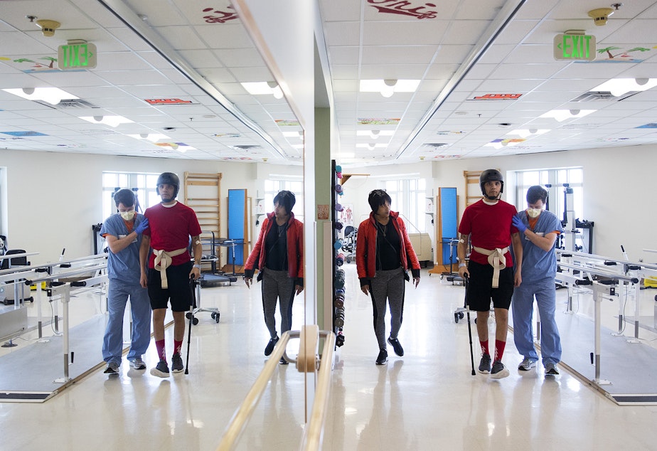 caption: DaShawn Horne learns how to walk again as his physical therapist Trevor Bouten holds him up, as his mother LaDonna Horne watches on Thursday, April 26, 2018, at Harborview Medical Center in Seattle.