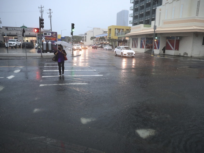 caption: A pedestrian tries to cross a flooded Queen Street, Monday, Dec. 6, 2021, in Honolulu.