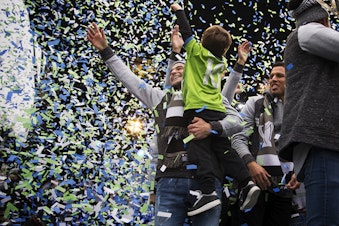 caption: Seattle Sounders team captain Nicolás Lodeiro holds his 4-year-old son Leandro as confetti rains down on them on Tuesday, November 12, 2019, during the MLS Cup Champions Parade and Rally at Seattle Center.