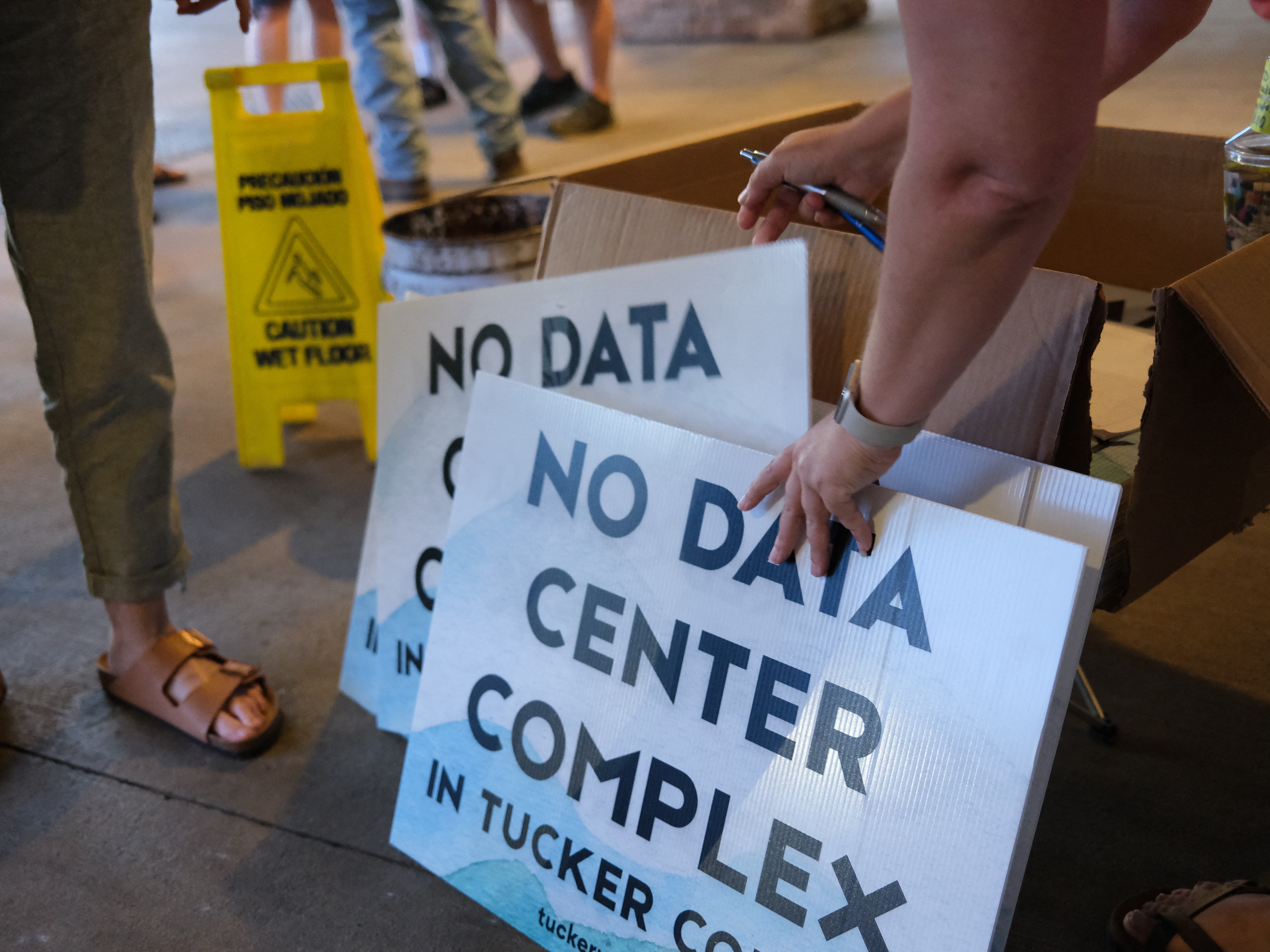 caption: Volunteers hand out yard signs in June against a data center complex in West Virginia.