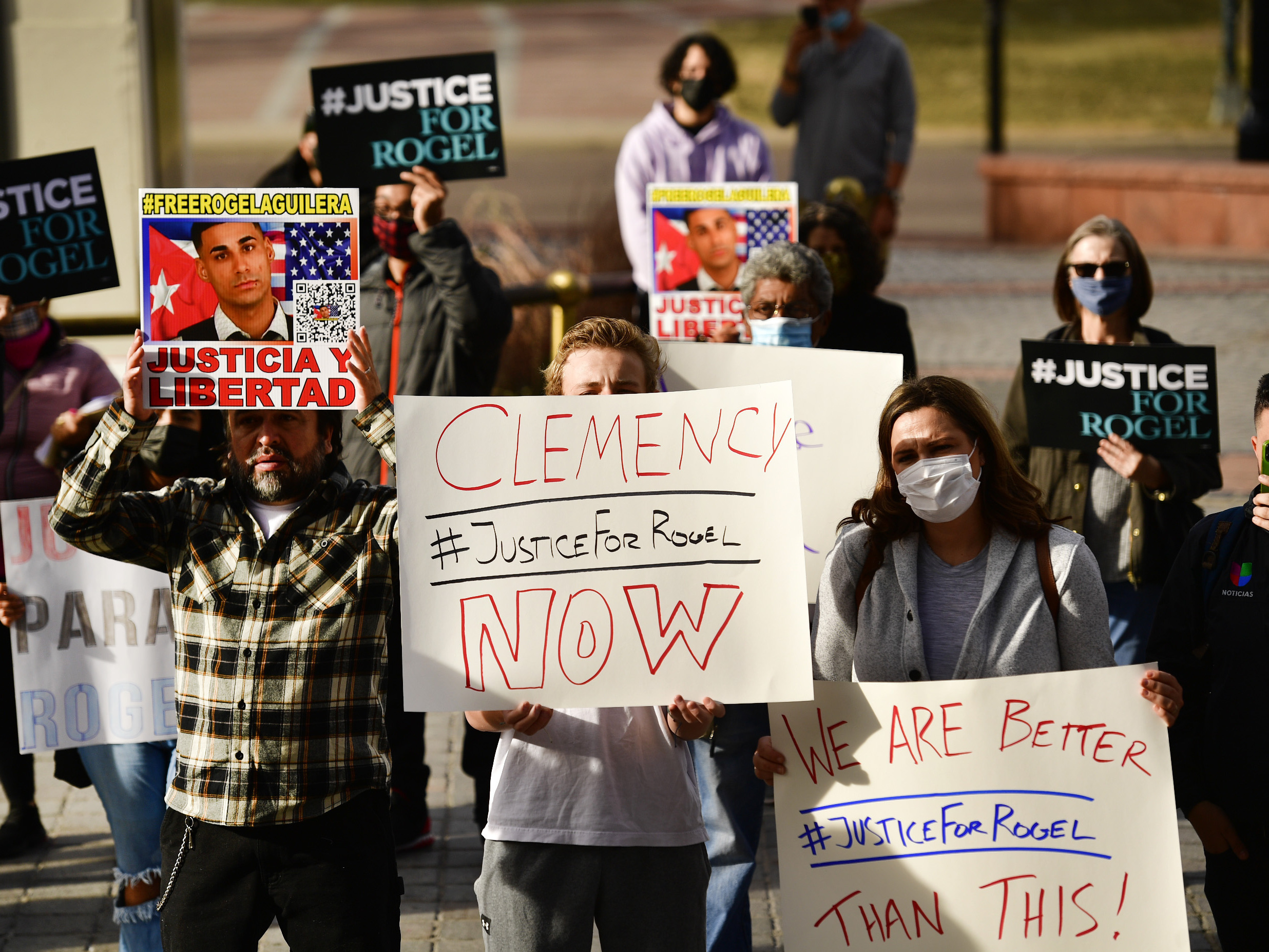 caption: People hold signs in support of truck driver Rogel Aguilera-Mederos during a rally on the west steps of the Colorado state capitol on Dec. 22 in Denver.