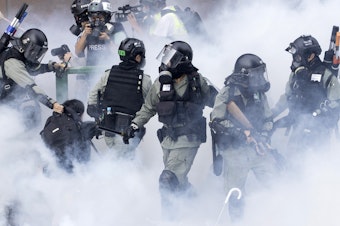 caption: Police in riot gear move through a cloud of smoke as they detain a protester, in November. Freedom House cited the willingness of people in Hong Kong to protest as encouraging.
