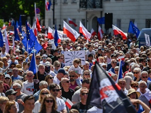 caption: Supporters of Poland's opposition parties hold European Union, Polish flags and banners during a march organized by Civil Platform on June 4, in Warsaw, Poland.