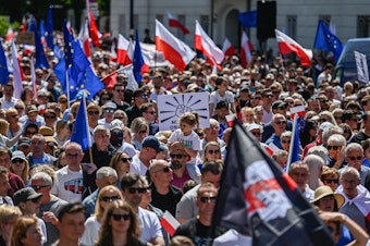 caption: Supporters of Poland's opposition parties hold European Union, Polish flags and banners during a march organized by Civil Platform on June 4, in Warsaw, Poland.