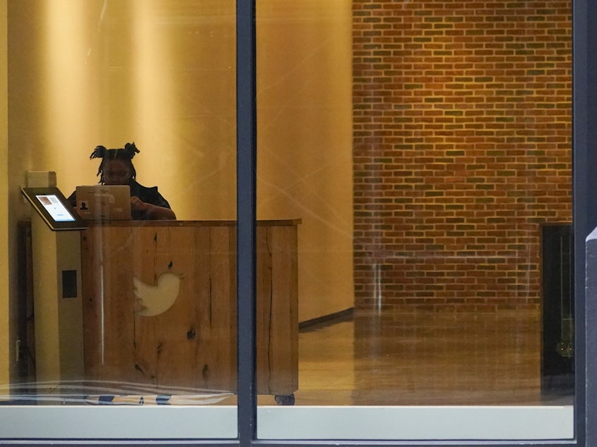 caption: A receptionist works in the lobby of the building that houses the Twitter office in New York, Wednesday, Oct. 26, 2022.
