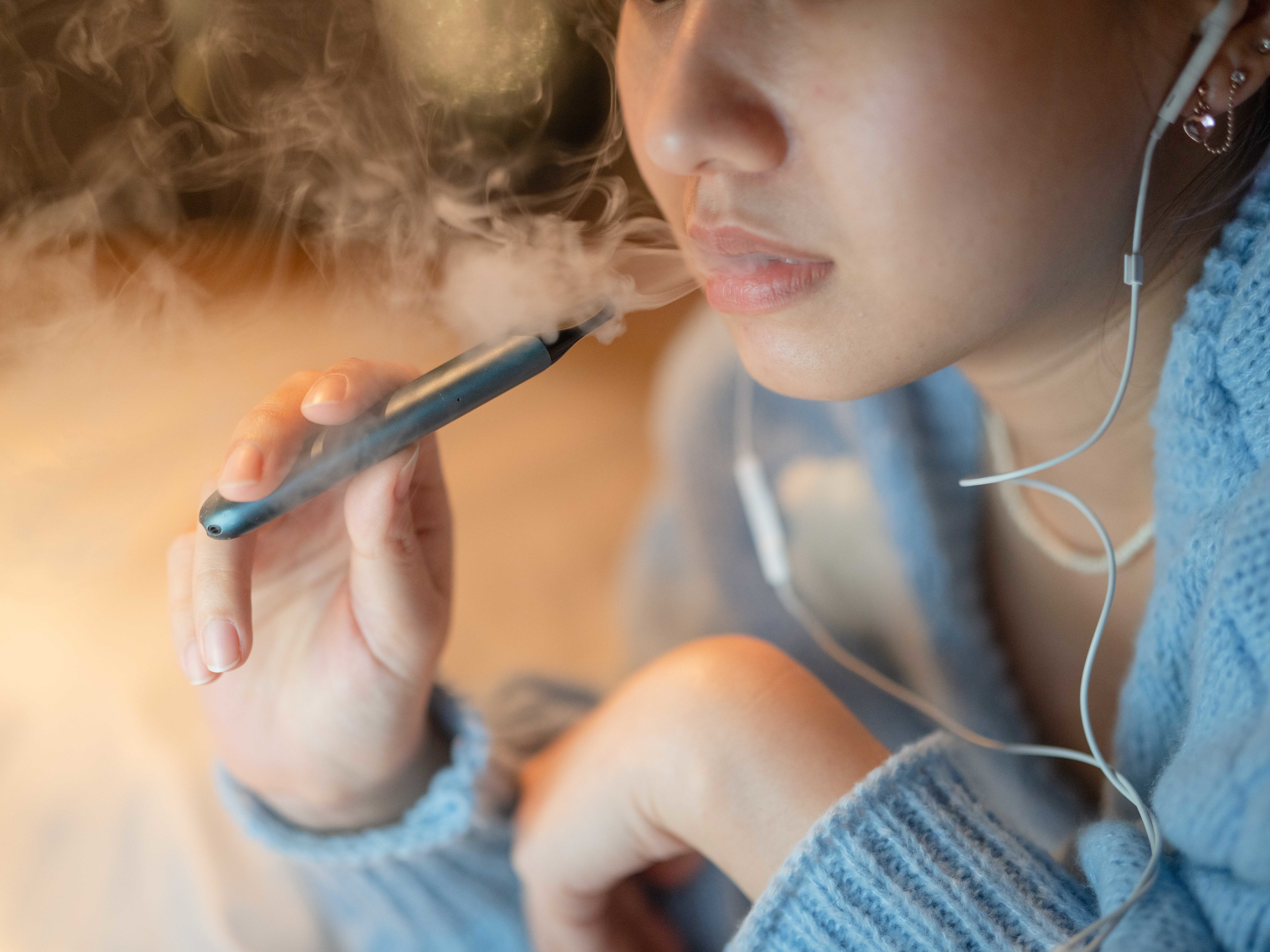 caption: A young woman vapes an electronic cigarette. Some districts are installing high-tech vape detectors to alert school officials if students are using e-cigarettes.