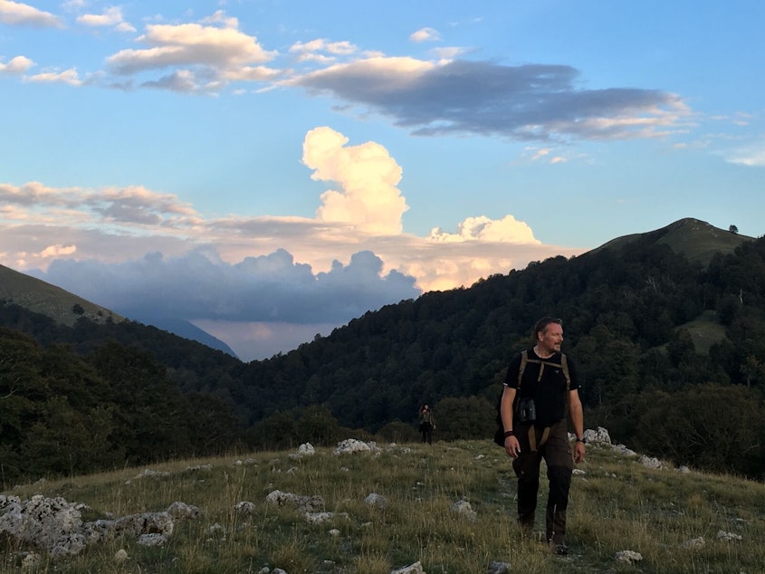 caption: Host Chris Morgan reaching a ridge high in the brown bear country of central Italy with amazing views of Europe's oldest beech forests