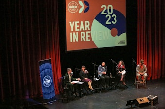 caption: Bill Radke looks back at the stories from 2023 with KUOW’s Monica Nickelsburg, Cat Smith and Mike Davis, Wing Luke Museum Executive Director Joël Barraquiel Tan, sports journalist and author Art Thiel, and author and podcaster Lindy West. 