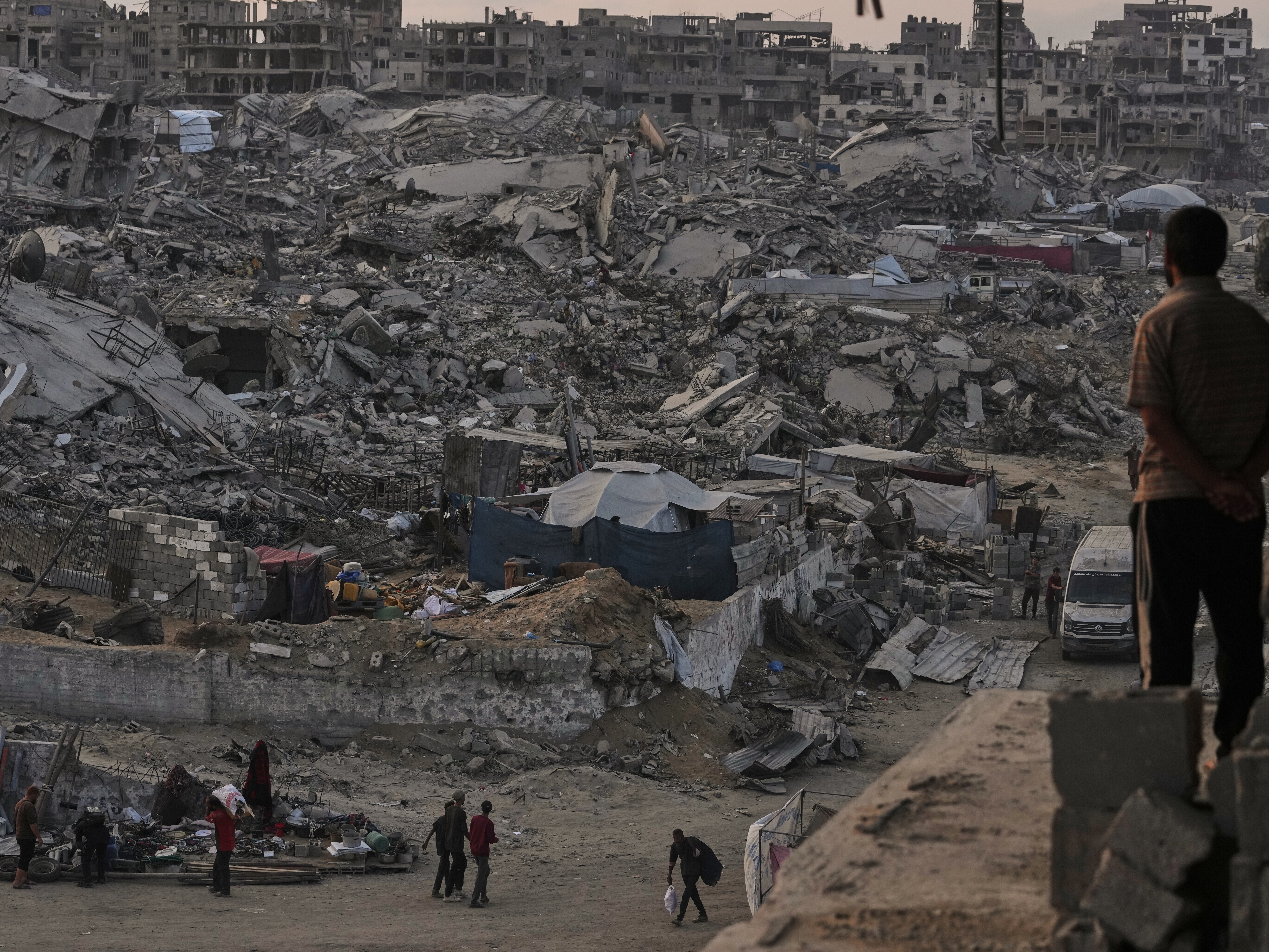 caption: Palestinians walk through the destruction caused by the Israeli air and ground offensive in Sheikh Radwan neighborhood in Gaza City.
