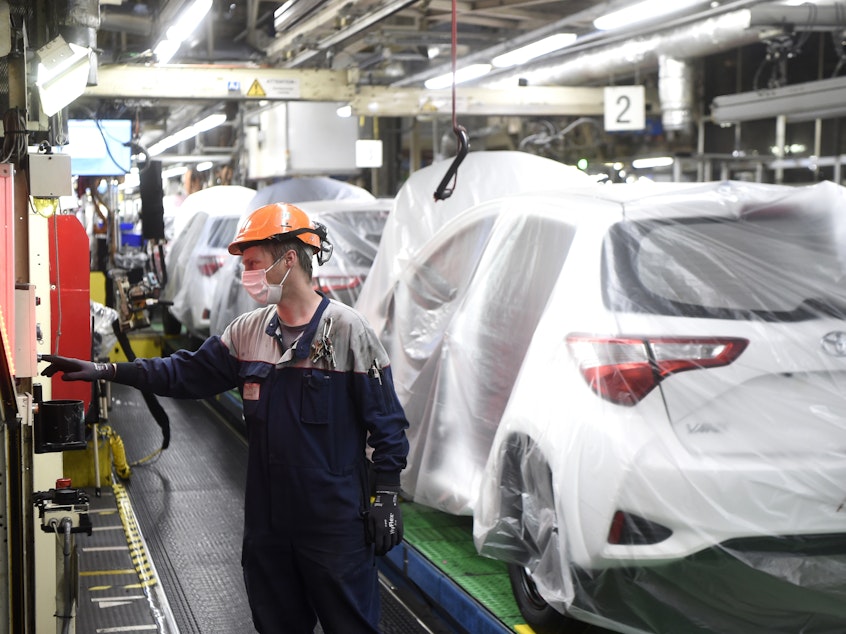 caption: An employee of Toyota company works on an assembly line on April 21, 2020 in Onnaing, northern France.