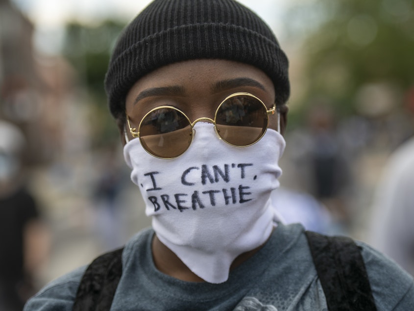 caption: Protests over police treatment of black people have sparked concerns over the possible spread of COVID-19. Here, a protestor marches with a cloth mask stating "I CAN'T BREATHE" in Philadelphia on Monday.
