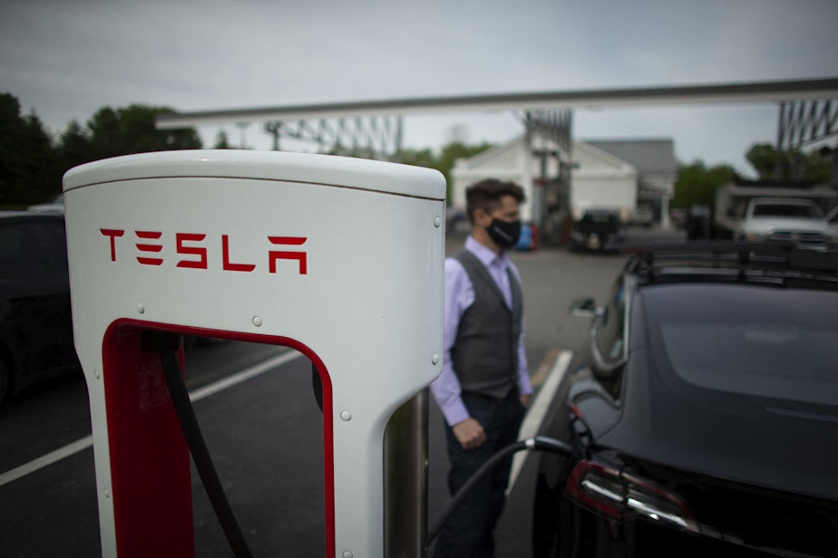 caption: Ben Rich charges his Tesla vehicle at a super charging station in New Jersey. (KENA BETANCUR/AFP via Getty Images)